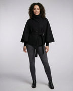 Full-length front view of the black belted cape coat styled with grey jeans and black ankle boots