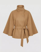 Camel-coloured belted cape jacket with asymmetric button stand collar, shown flat against a white background
