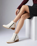 Off-white ankle boots with side zip pull and block heel, paired with a burgundy jumper and black skirt