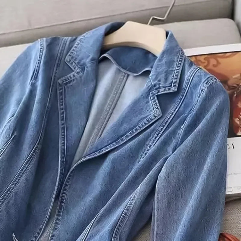 Close-up of the denim blazer's lapel and collar detail, highlighting the textured washed denim fabric and visible topstitching