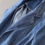 Close-up of the open denim blazer showing the inner lining, notch lapel stitching and the softly faded indigo wash of the fabric