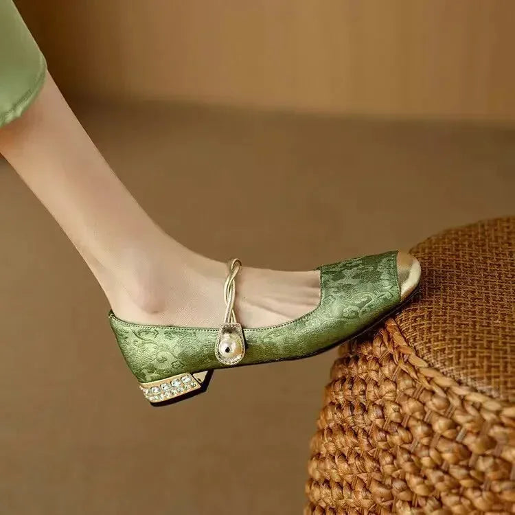 Angled view of the green flat resting on a woven basket, highlighting the sparkling heel detail