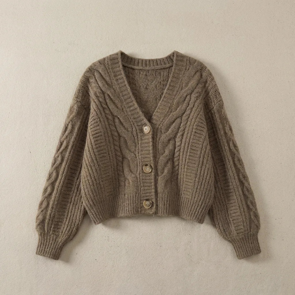 Taupe brown cable-knit cropped cardigan with ribbed cuffs and V-neckline, laid flat on a textured surface