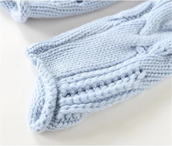 Close-up of the ribbed cuff on a light blue sleeve, showing the folded knit edge and cable detailing