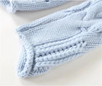 Close-up of the ribbed cuff on a light blue sleeve, showing the folded knit edge and cable detailing