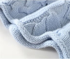 Macro shot of the light blue knit fabric showing the dense cable pattern and soft yarn texture