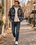 Navy, cream and brown checked hooded jacket with sherpa lining worn over a cream jumper, hands in pockets, autumn street scene