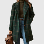 Woman wearing a green windowpane check wool coat open over a knit polo neck and jeans, front view