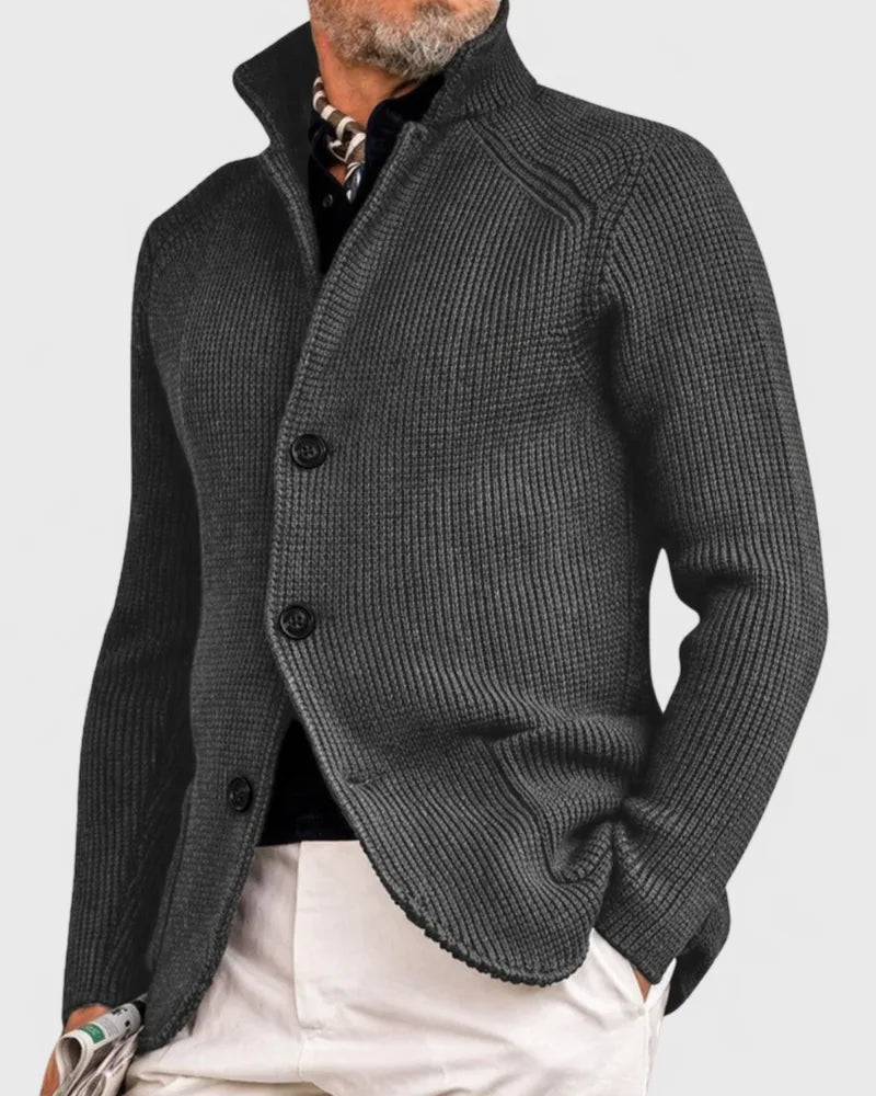 Charcoal grey waffle-knit cardigan with stand collar, shown buttoned with hand resting near pocket