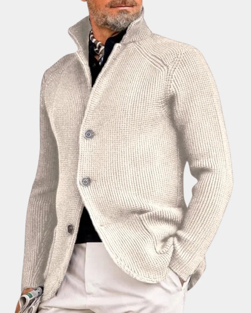Cream off-white chunky knit cardigan with stand collar and button closure, worn with white trousers