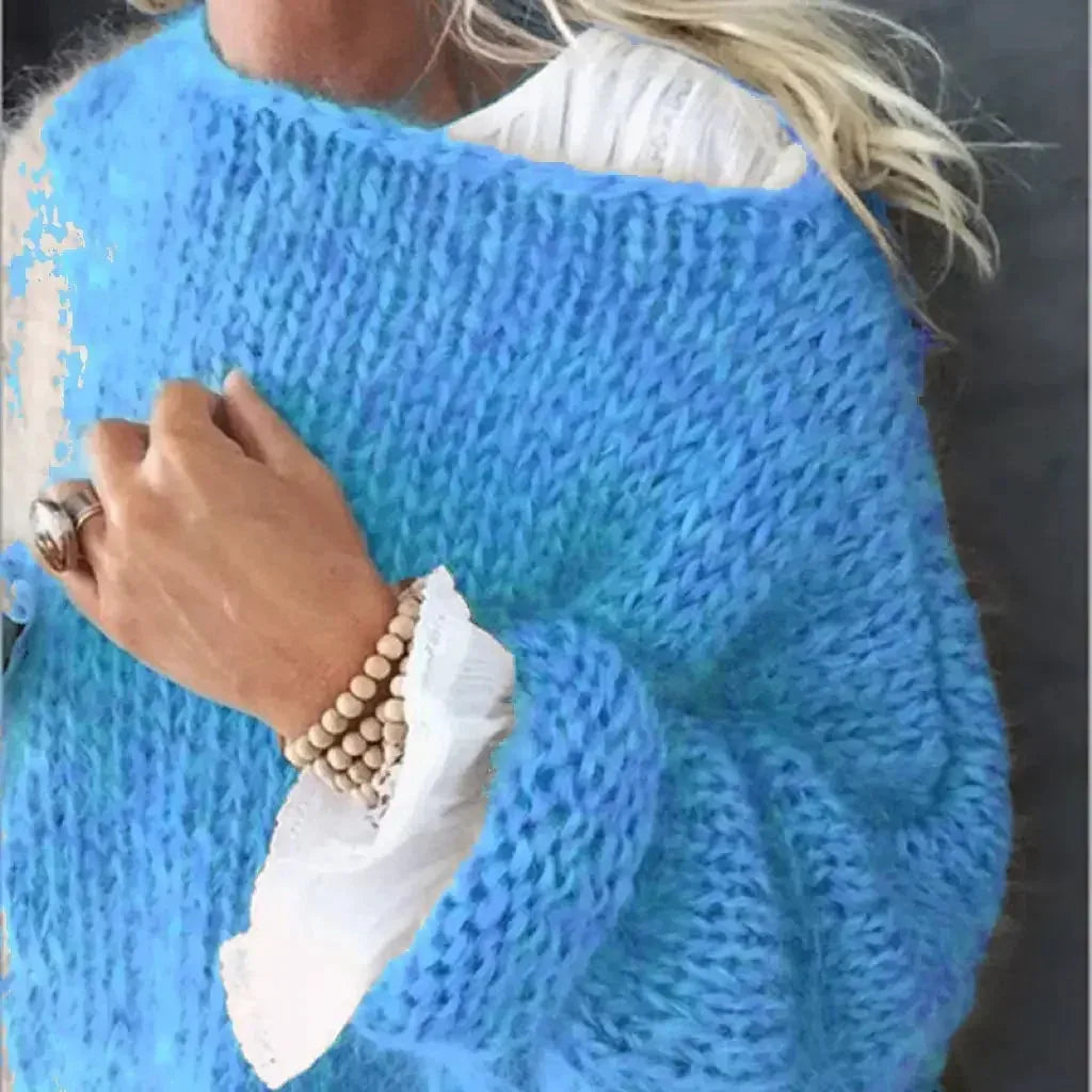 Close-up of a bright blue chunky knit jumper texture with ribbed sleeve and layered white cuff