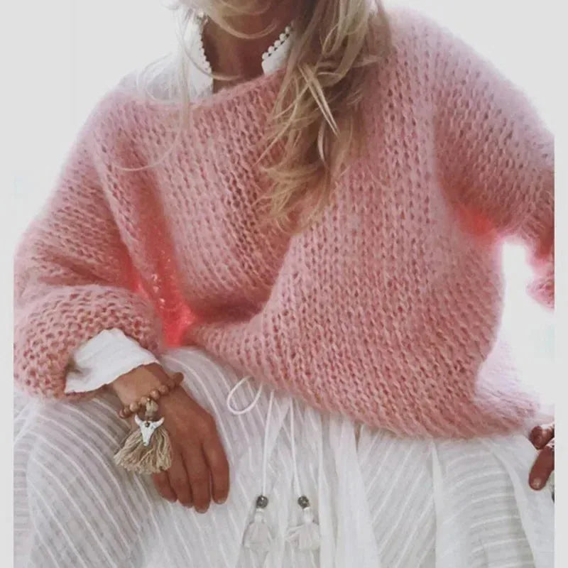 Front view of a pale pink loose knit jumper worn over a white lace-trim top with a boho outfit