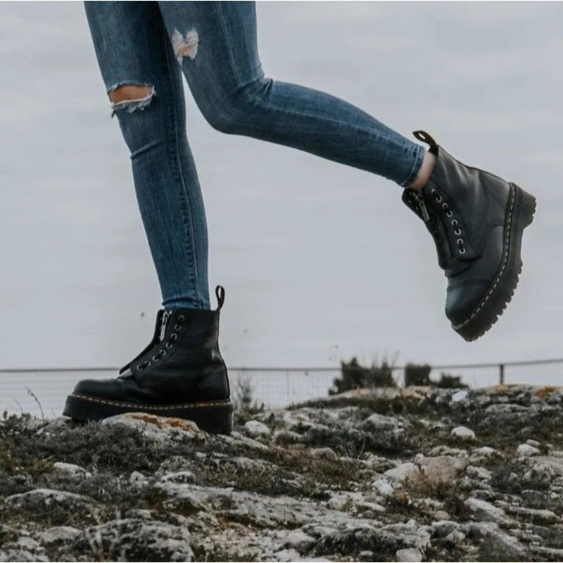 Side profile of a model stepping forward in black chunky platform boots paired with ripped skinny jeans outdoors