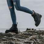 Side profile of a model stepping forward in black chunky platform boots paired with ripped skinny jeans outdoors