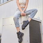 Woman sitting with legs crossed, wearing black platform boots with turned-up light denim jeans