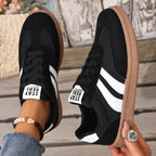 Top and side view of black suede trainers with white stripes and gum sole