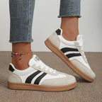 Close-up side profile of white and black striped trainer worn with cropped jeans