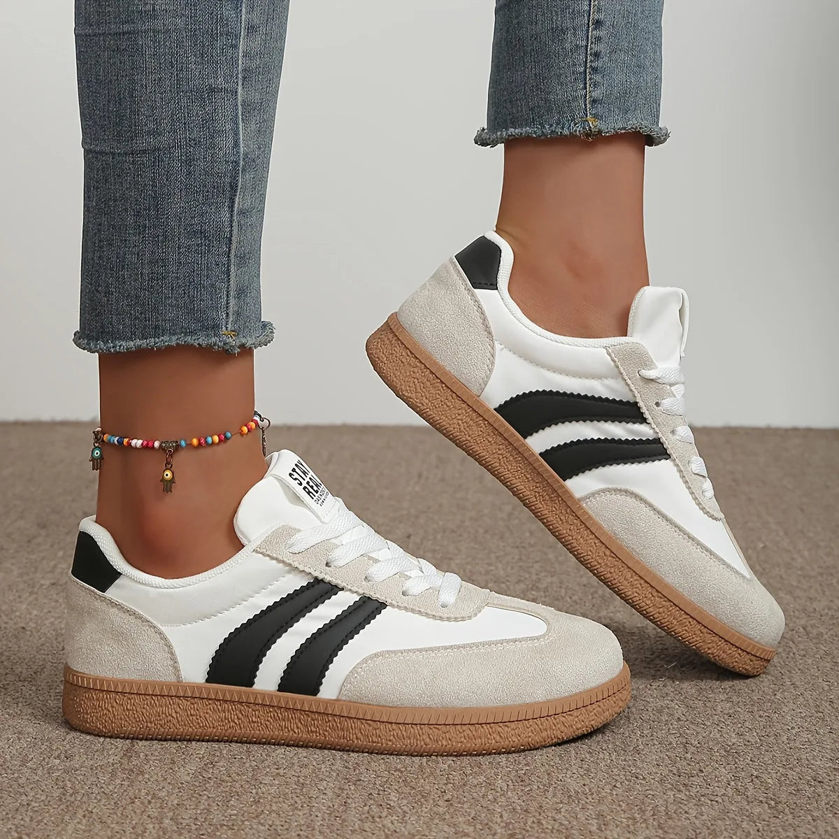 Close-up side profile of white and black striped trainer worn with cropped jeans