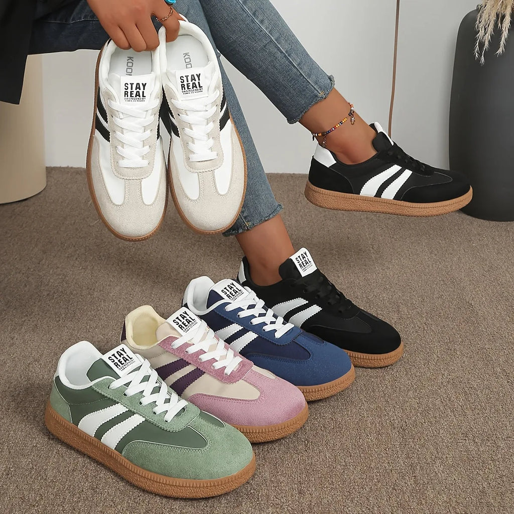 Four colourways of lace-up trainers lined up, including white, black, navy, pink and green pairs