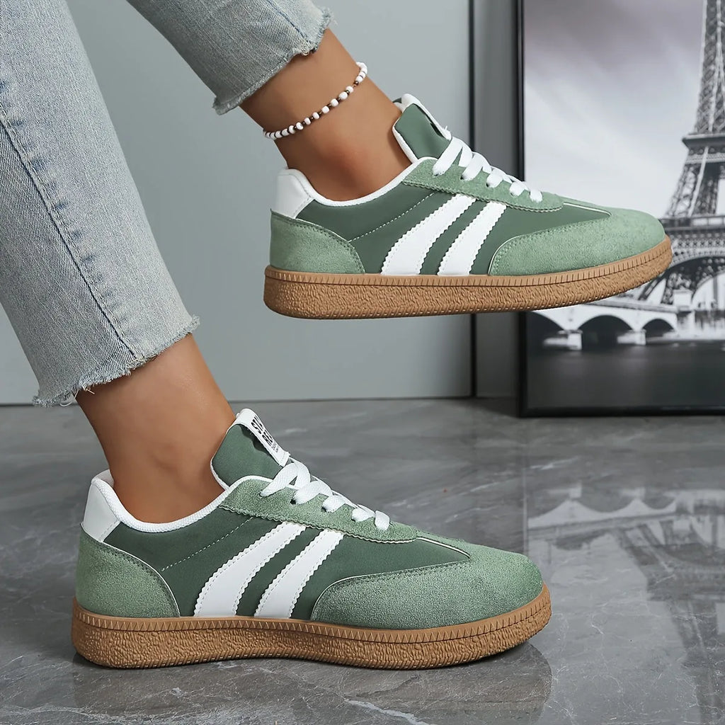 Side view of sage green suede trainer with white stripes worn on foot near Eiffel Tower photo