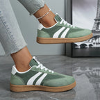 Side view of sage green suede trainer with white stripes worn on foot near Eiffel Tower photo