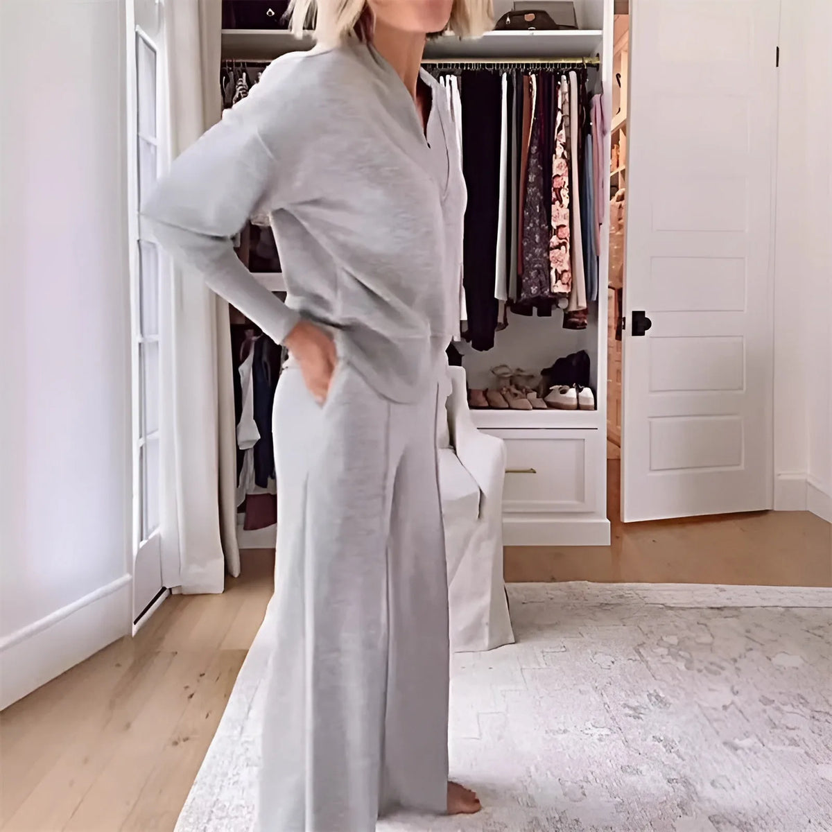 Side view of a woman in the grey two-piece set with hand on hip, showing the flowing wide-leg trousers