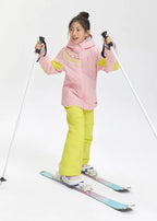 Front view of a girl wearing a pink hooded ski jacket with yellow sleeve panels, holding ski poles