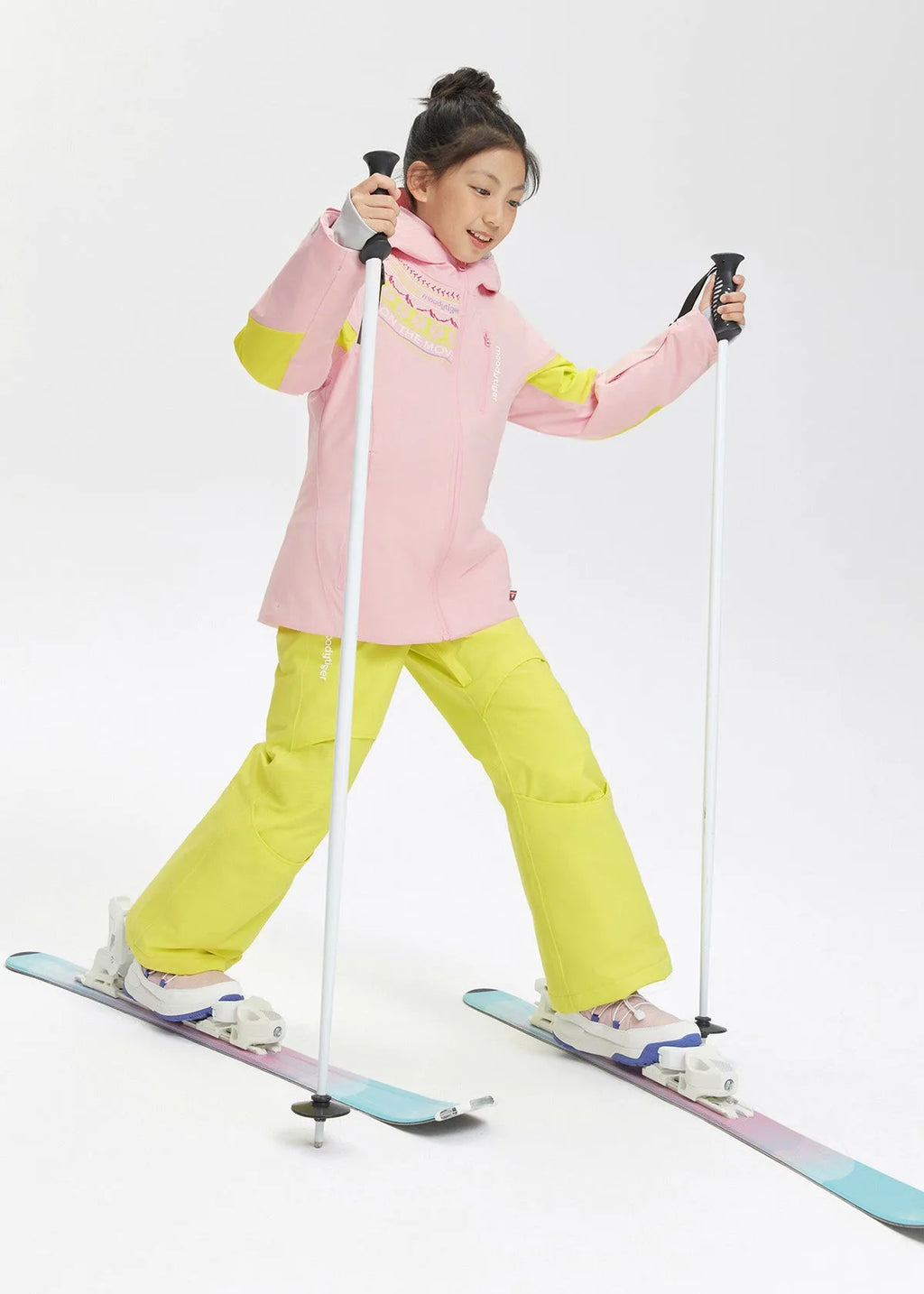 Side view of a girl in a pink and lime ski jacket paired with matching yellow ski trousers