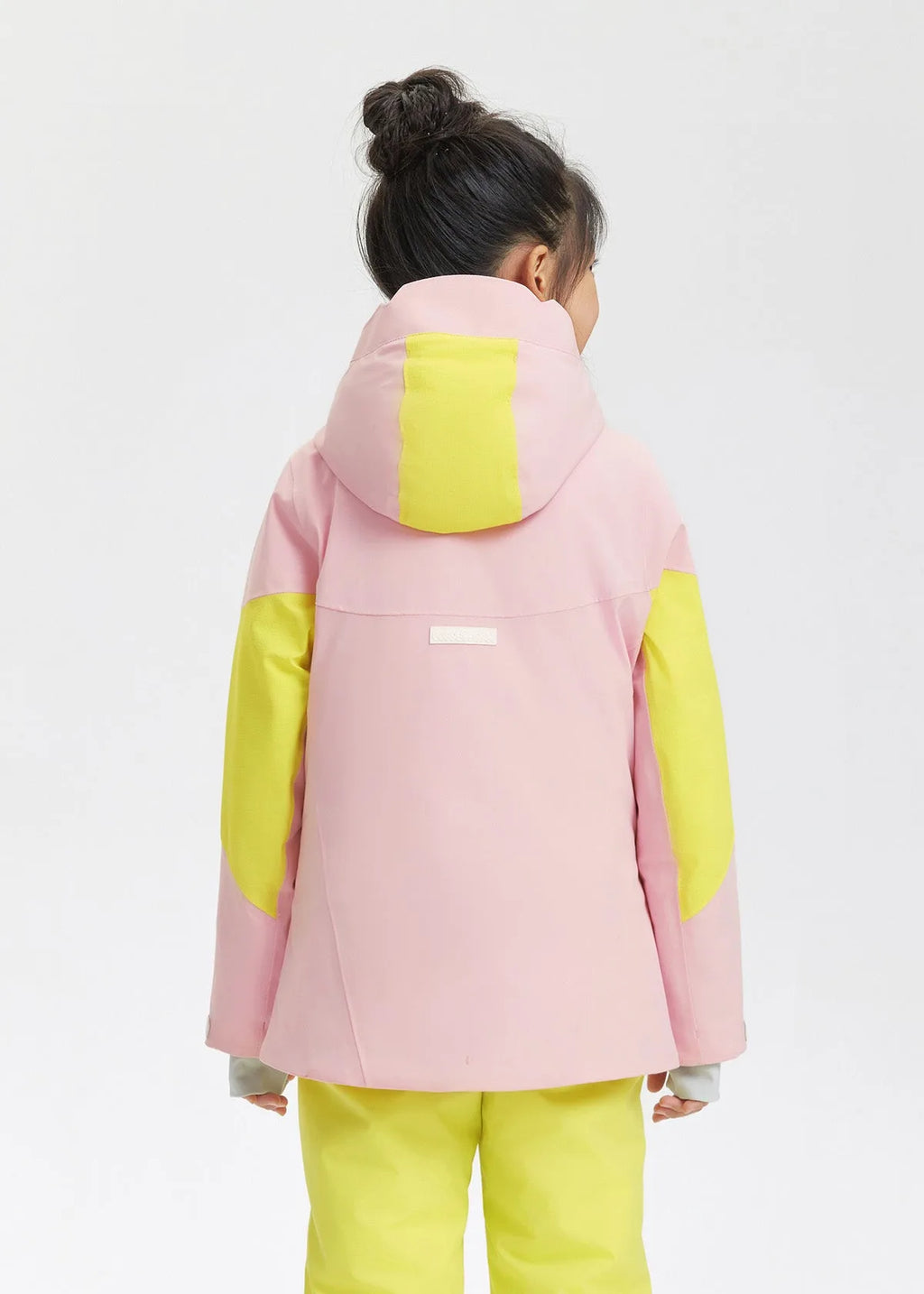 Back view showing the pink hooded jacket with yellow shoulder and hood panels and brand tab