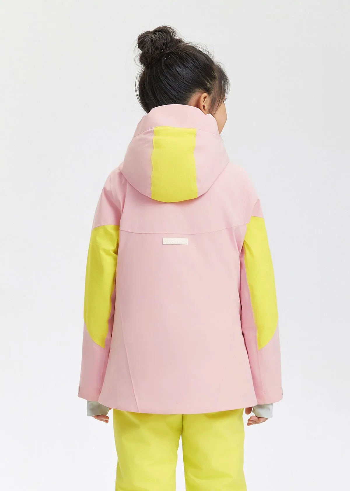 Back view showing the pink hooded jacket with yellow shoulder and hood panels and brand tab