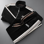 Black corduroy zip-up jacket and matching joggers folded together, showing brown and cream side stripes and drawstring waist