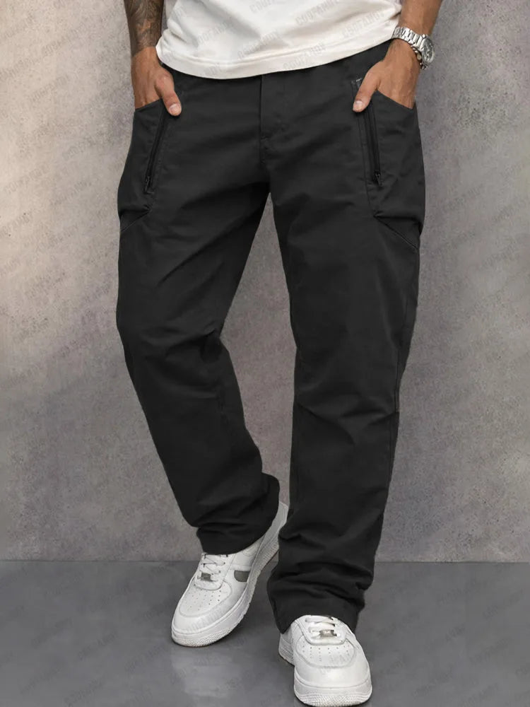 Model wearing black cotton cargo trousers with zippered side pockets and straight leg silhouette