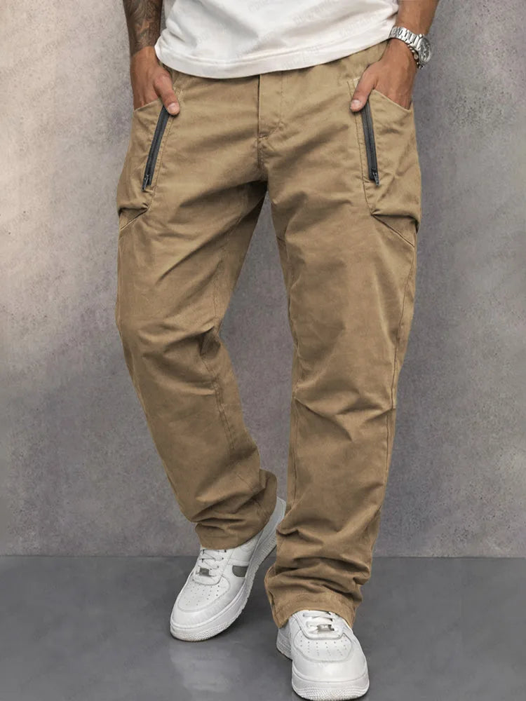 Close-up front view of tan cargo trousers showing zip pockets and structured waistband