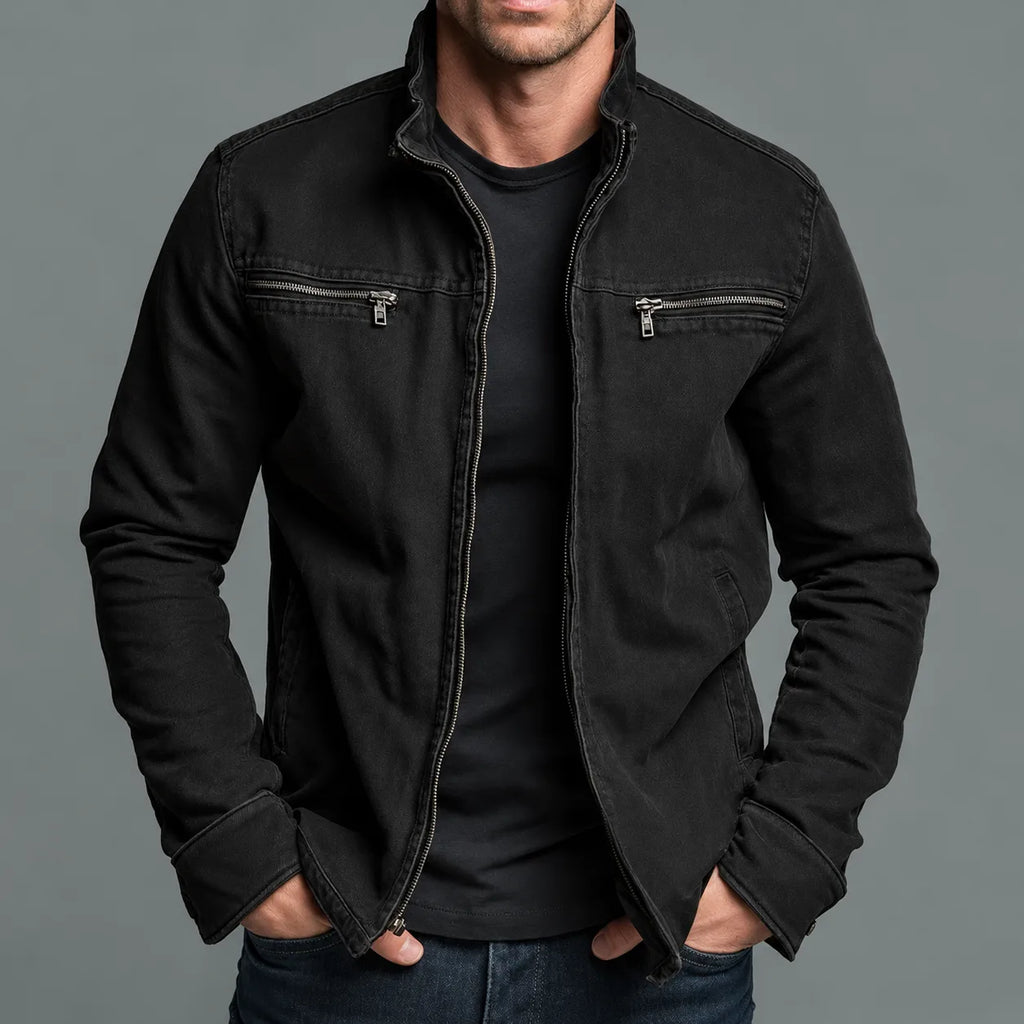 Man wearing a faded black cotton zip jacket with stand collar and twin chest zip pockets, hands in pockets