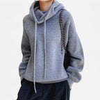 Grey marl cowl neck knit hoodie worn with a chain-strap handbag and dark trousers