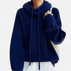 Navy blue cowl neck knit hoodie worn with a cream tote bag, showing relaxed oversized fit