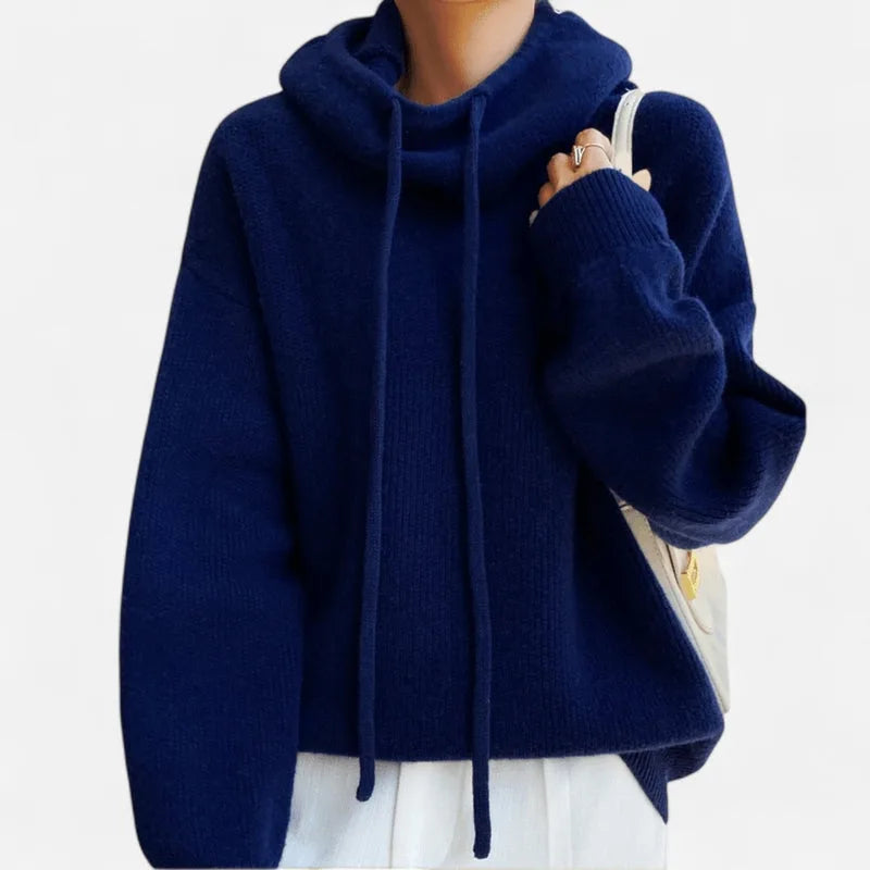 Navy blue cowl neck knit hoodie worn with a cream tote bag, showing relaxed oversized fit