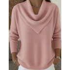 Front view of a dusty pink knitted jumper with a draped cowl neckline and ribbed cuffs, worn with white trousers