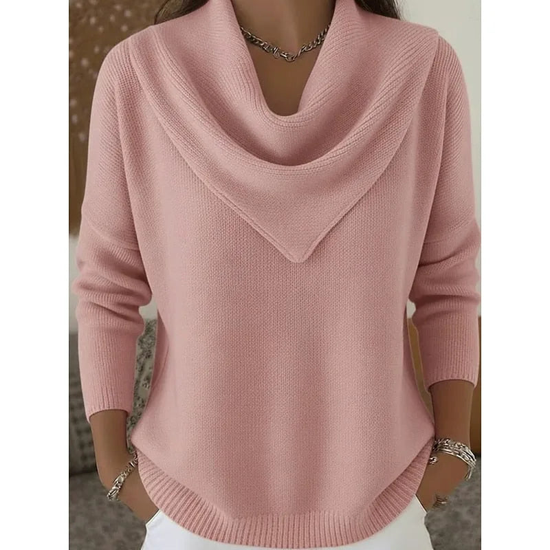 Front view of a dusty pink knitted jumper with a draped cowl neckline and ribbed cuffs, worn with white trousers