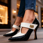 Side view of black croc-embossed stiletto pump with ivory T-strap and gold buckle, worn with cropped jeans