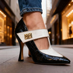 Close-up of black and white T-strap heel showing the pointed toe and slim heel on a city street