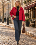 Red short jacket with lapel collar and gingham cuff trim, buttoned up over a black polo neck and jeans