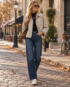 Stone-coloured short jacket with checked lining worn open over denim, styled with sunglasses, trainers and a shoulder bag