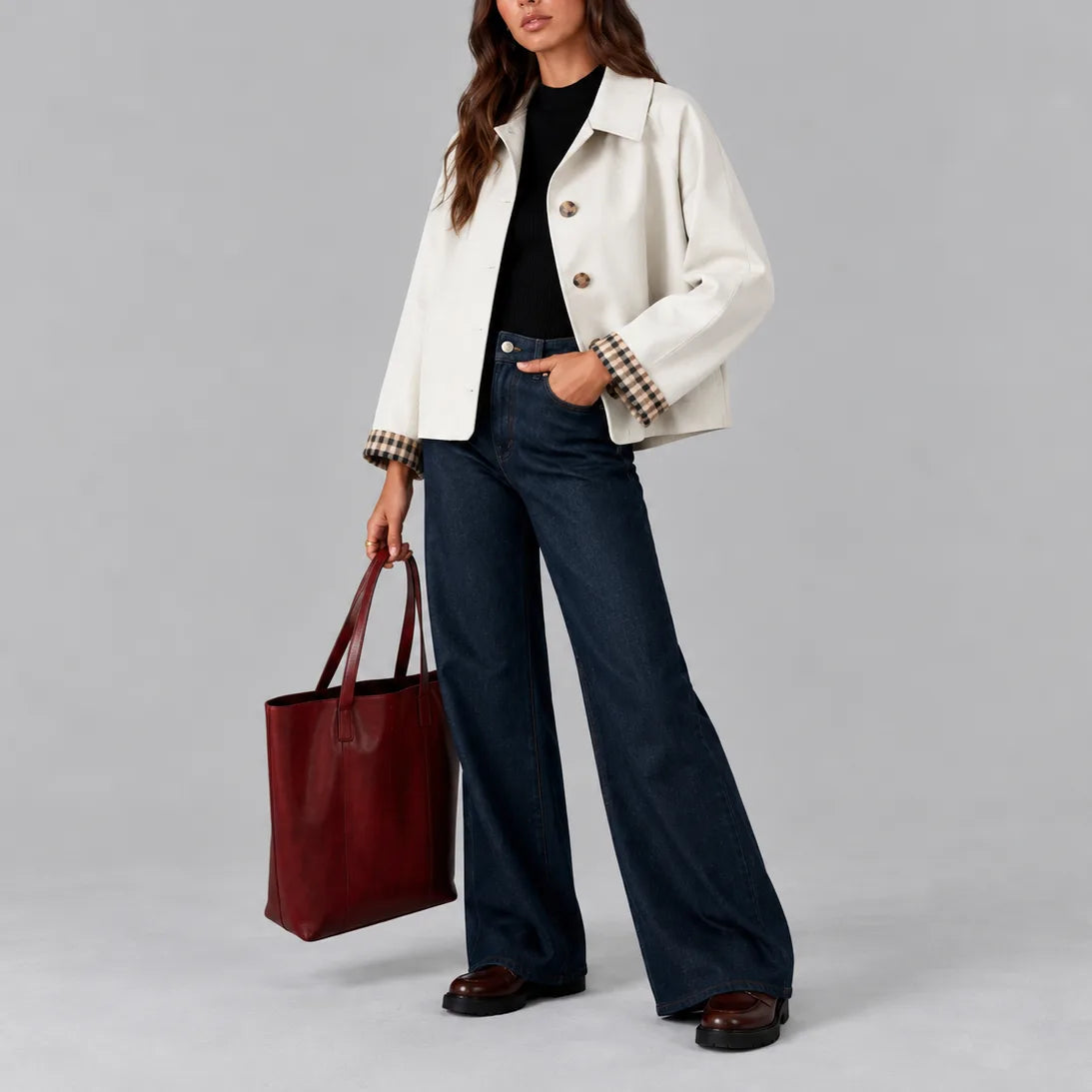 Front view of a white cropped trench jacket worn open over a black jumper and dark wide-leg jeans