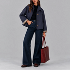 Front view of a navy cropped trench jacket buttoned up, styled with dark wide-leg denim