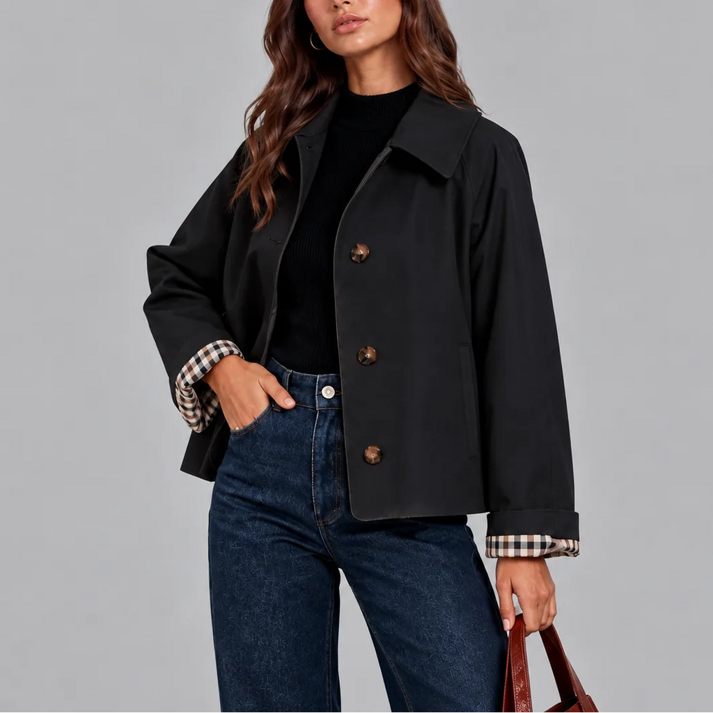 Close-up of a black cropped trench jacket showing the tortoiseshell buttons and collar detail