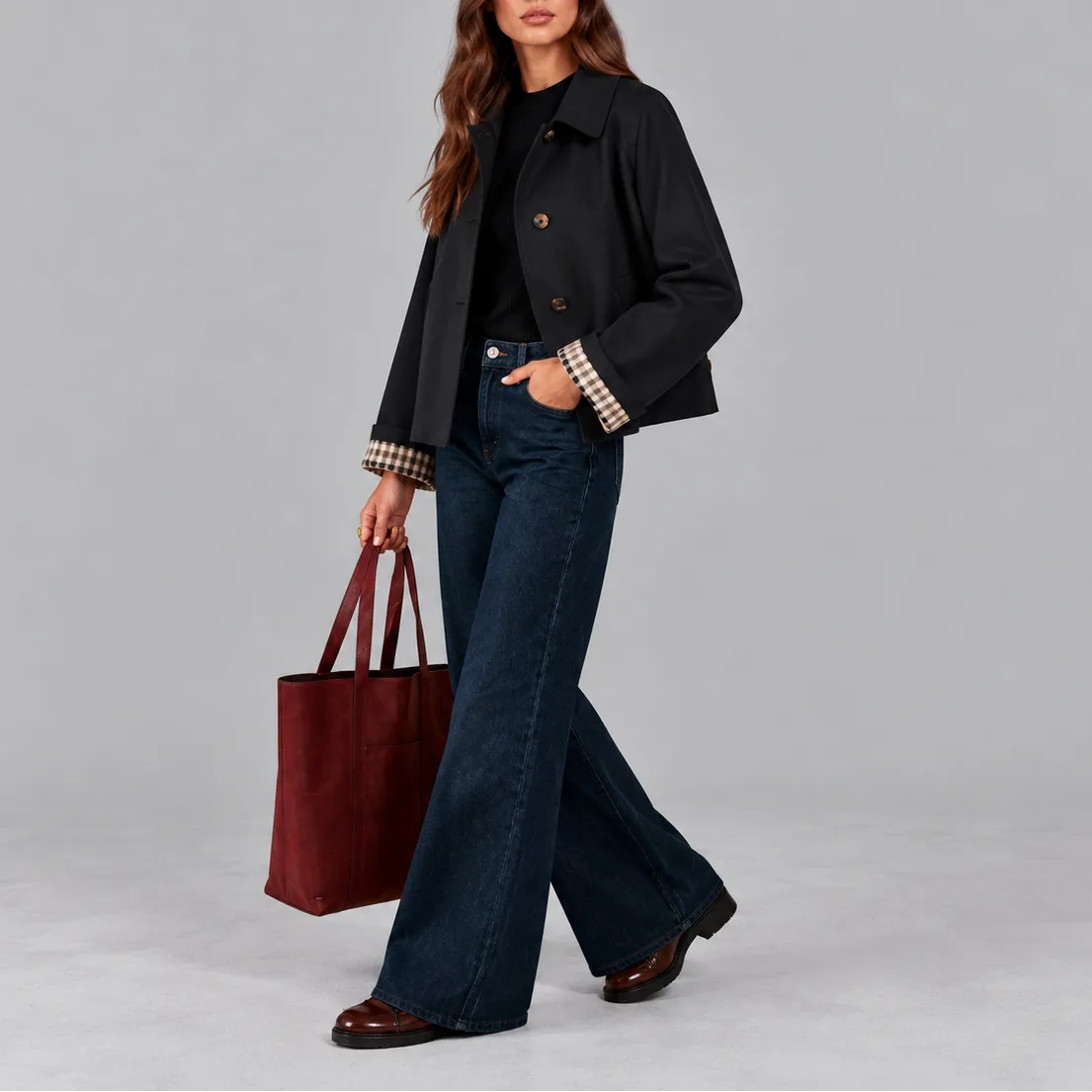 Side view of the black cropped jacket worn while walking, showing the checked lining at the cuffs