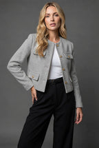 Detail shot of gold button fastening down the front of the light blue tweed cropped jacket