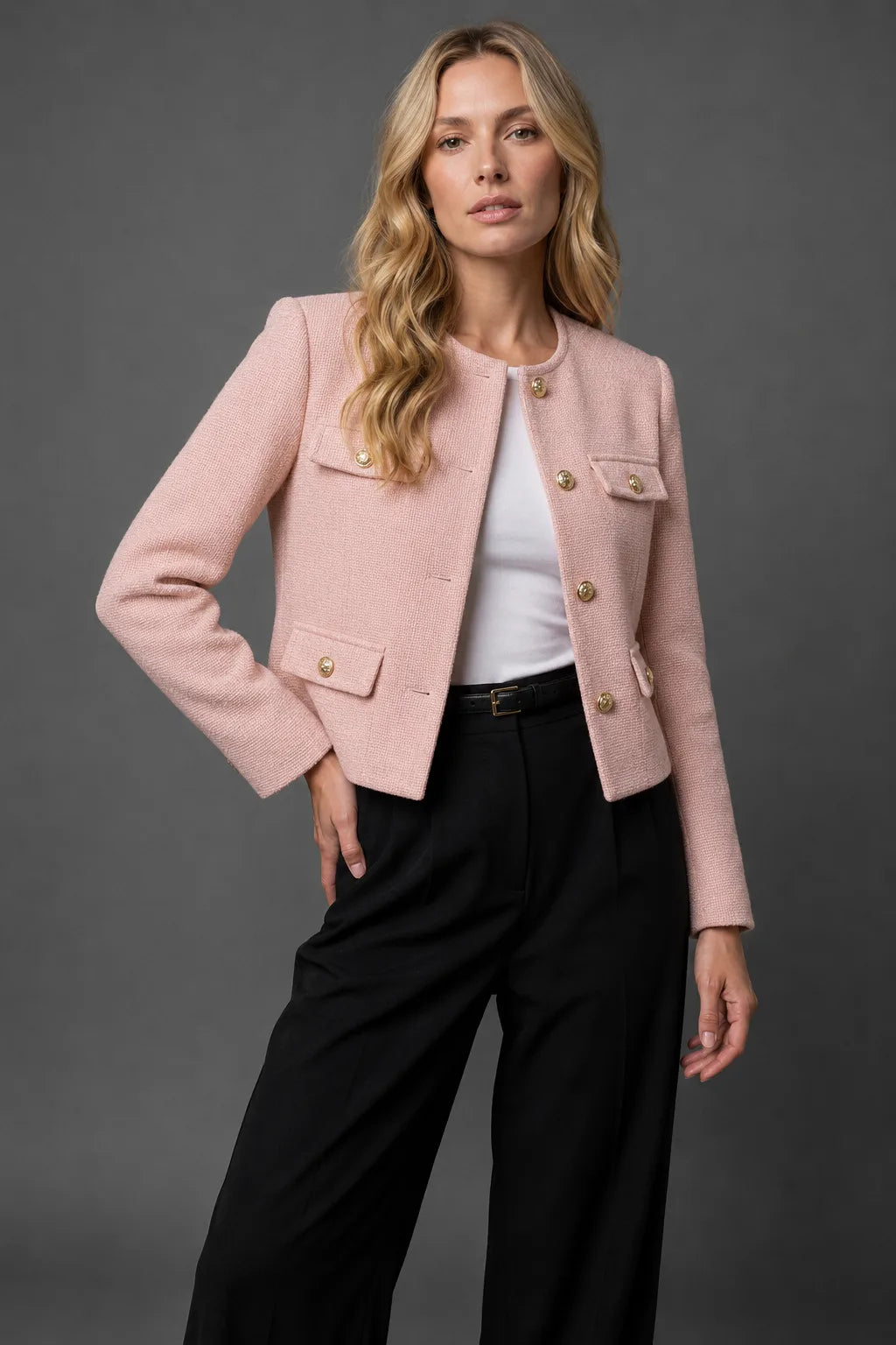 Three-quarter view of the black tweed jacket with hands in trouser pockets showing the jacket's cropped fit