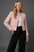 Three-quarter view of the black tweed jacket with hands in trouser pockets showing the jacket's cropped fit